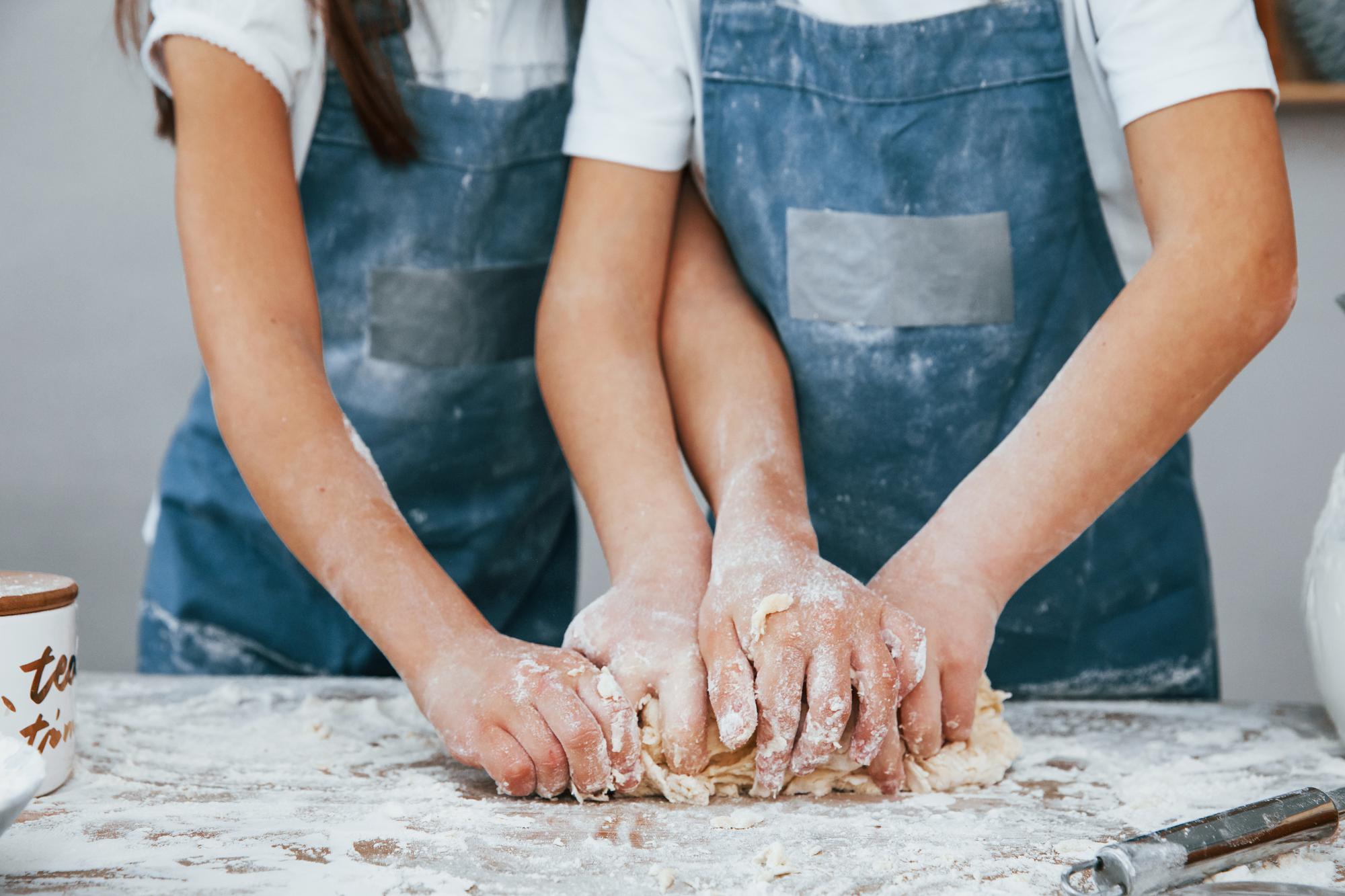 students kneading dough in a sunny kitchen